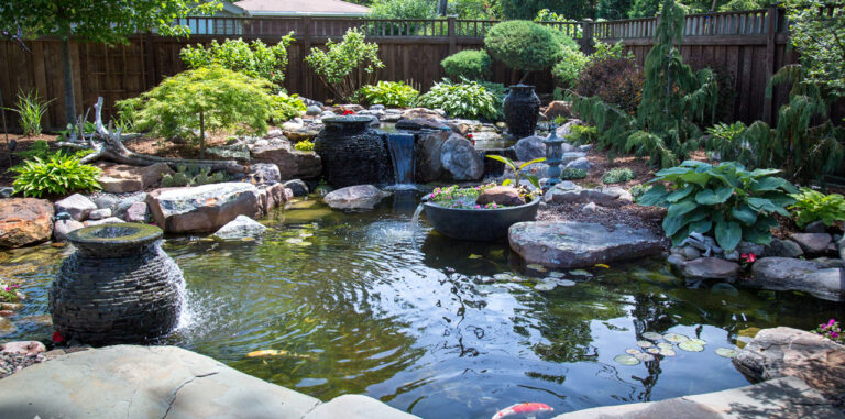 pond with decorative stacked slate urns and spillway bowl with koi and water lilies