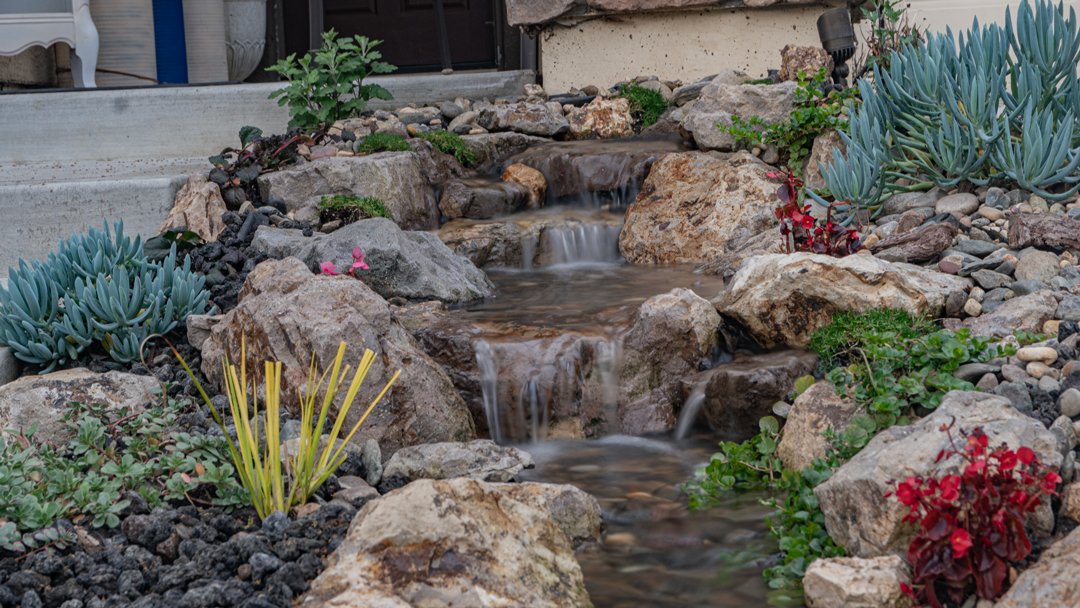 Garden water feature with flowing stream and rocks.