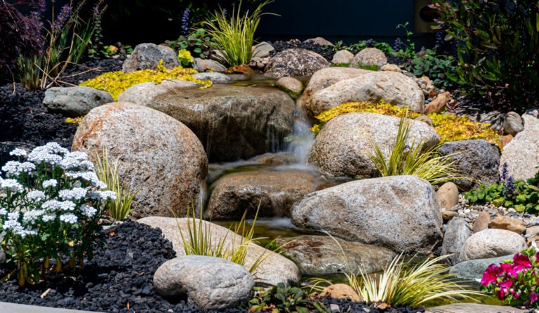 Garden dissapearing waterfall with rocks and colorful plants in the bay area ca