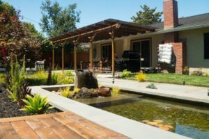 Backyard with pergola and small formal pond feature.