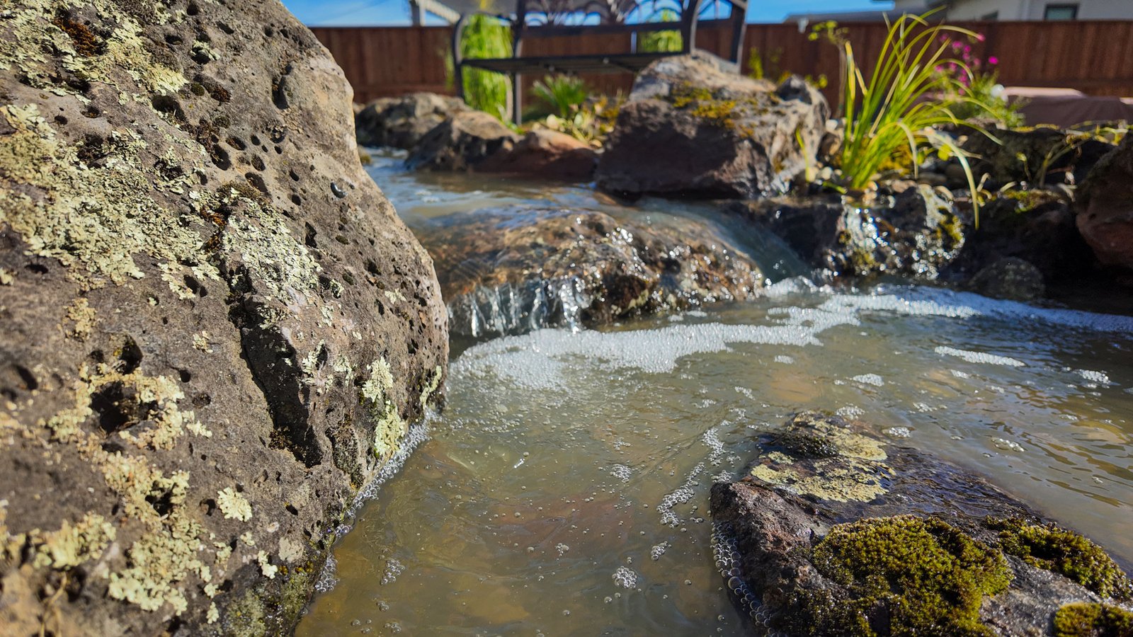 Small waterfall flowing over rocks in garden pond.