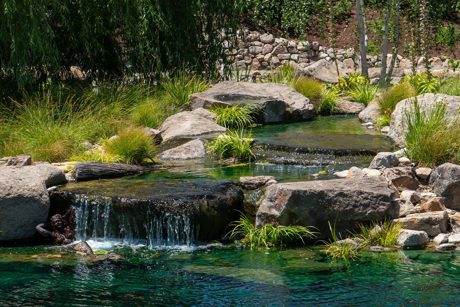 LArge waterfall into a koi pond with blue dye